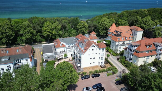 Una zona residenziale costiera con edifici a più piani, un parcheggio e vista sul mare.