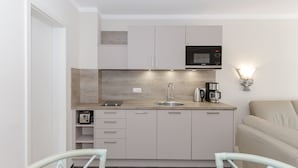 Cocina compacta con microondas, cafetera y lavabo. Cuenta con armarios y encimera.