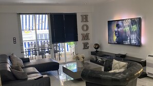 Een moderne woonkamer met een bank, een salontafel en een televisie aan de muur.