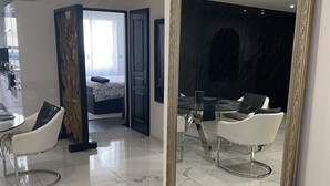 Een moderne woonkamer met een grote spiegel, een eettafel en twee witte stoelen.