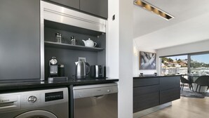 A modern kitchen with Bosch appliances, a built-in washer, and a view of a cityscape through large windows. - Seacliffe 502 (Cape Town)