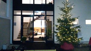 Un edificio moderno con entrada de vidrio, una escalera que lleva a un nivel superior y un árbol de Navidad decorado.