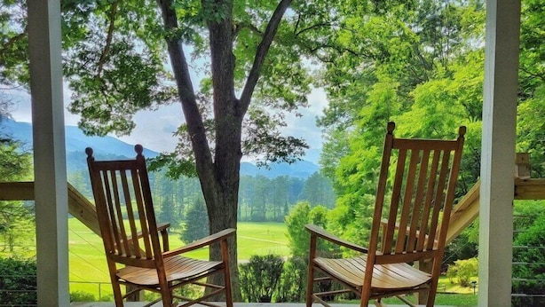 Two rocking chairs on a wooden deck with a view of a green landscape and mountains. - Fairway Mountain Retreat-Views-5min to Downtown (Waynesville)