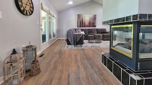 A spacious living room with a fireplace, a large clock, and a sofa. - Fairway Mountain Retreat-Views-5min to Downtown (Waynesville)