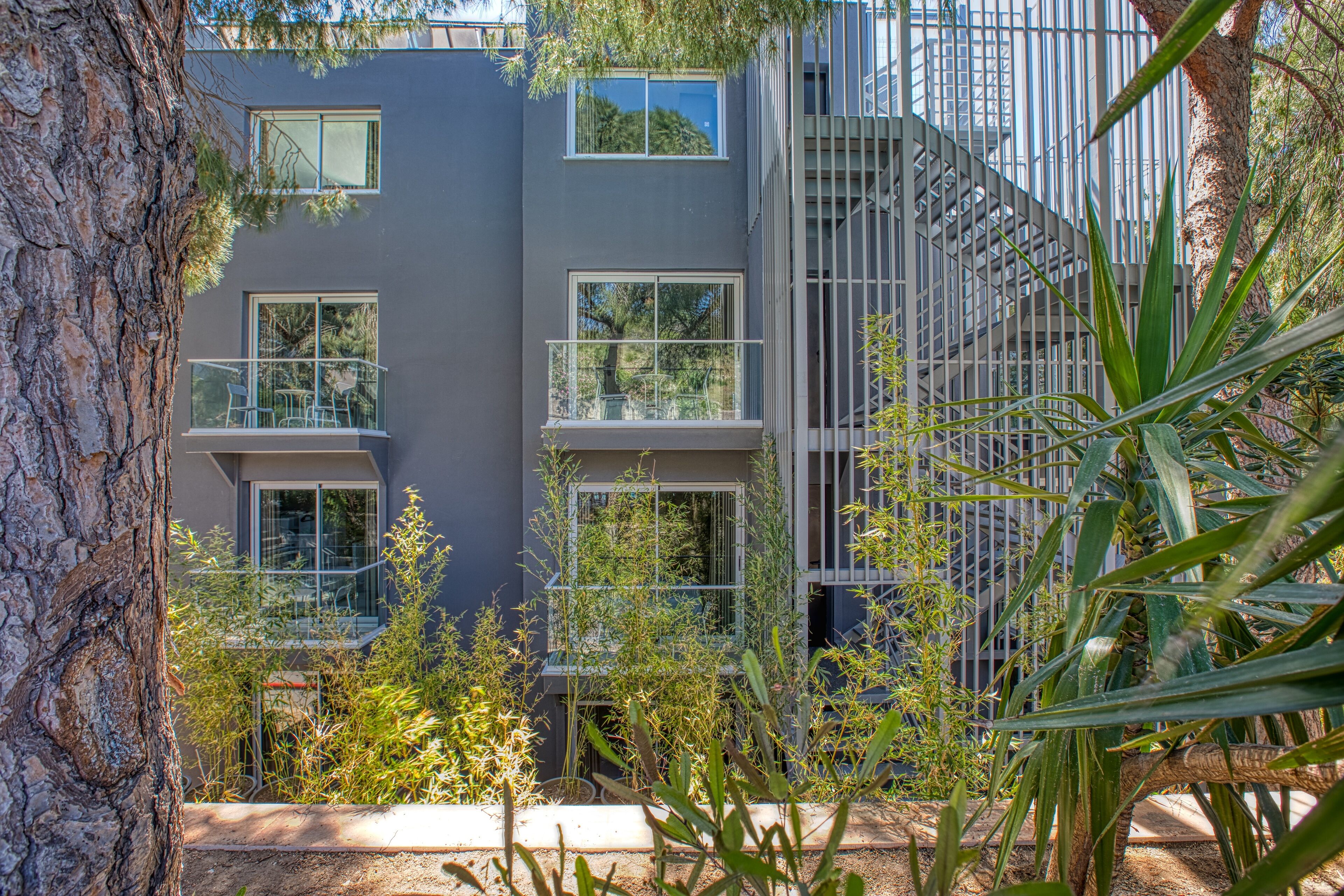 Un bâtiment moderne doté de nombreux balcons et de grandes fenêtres, entouré de verdure.