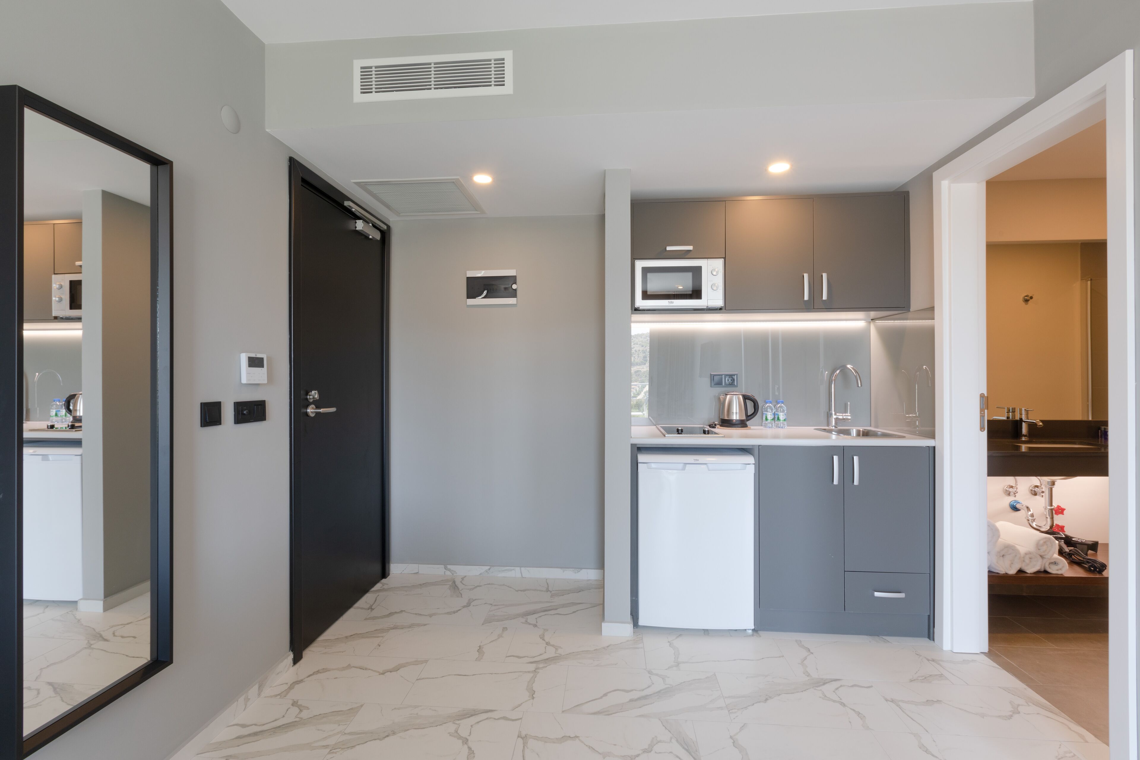 A compact kitchen with a microwave, sink, and a small refrigerator.