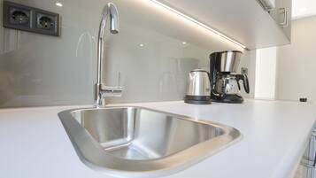 A modern kitchen with a stainless steel sink, a coffee maker, and a wall-mounted electrical outlet.