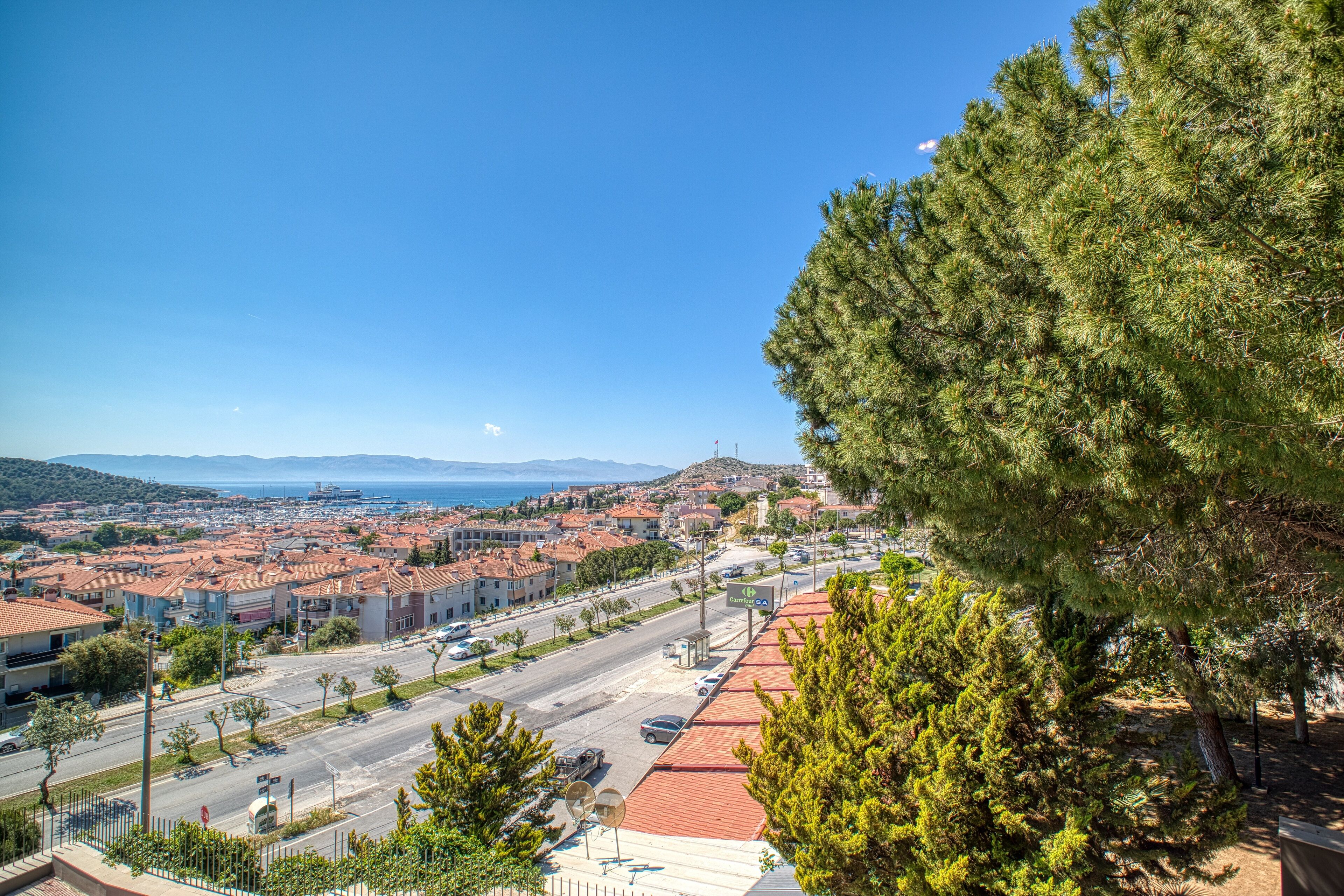 A coastal town with red-roofed buildings, a clear blue sky, and a view of the sea.