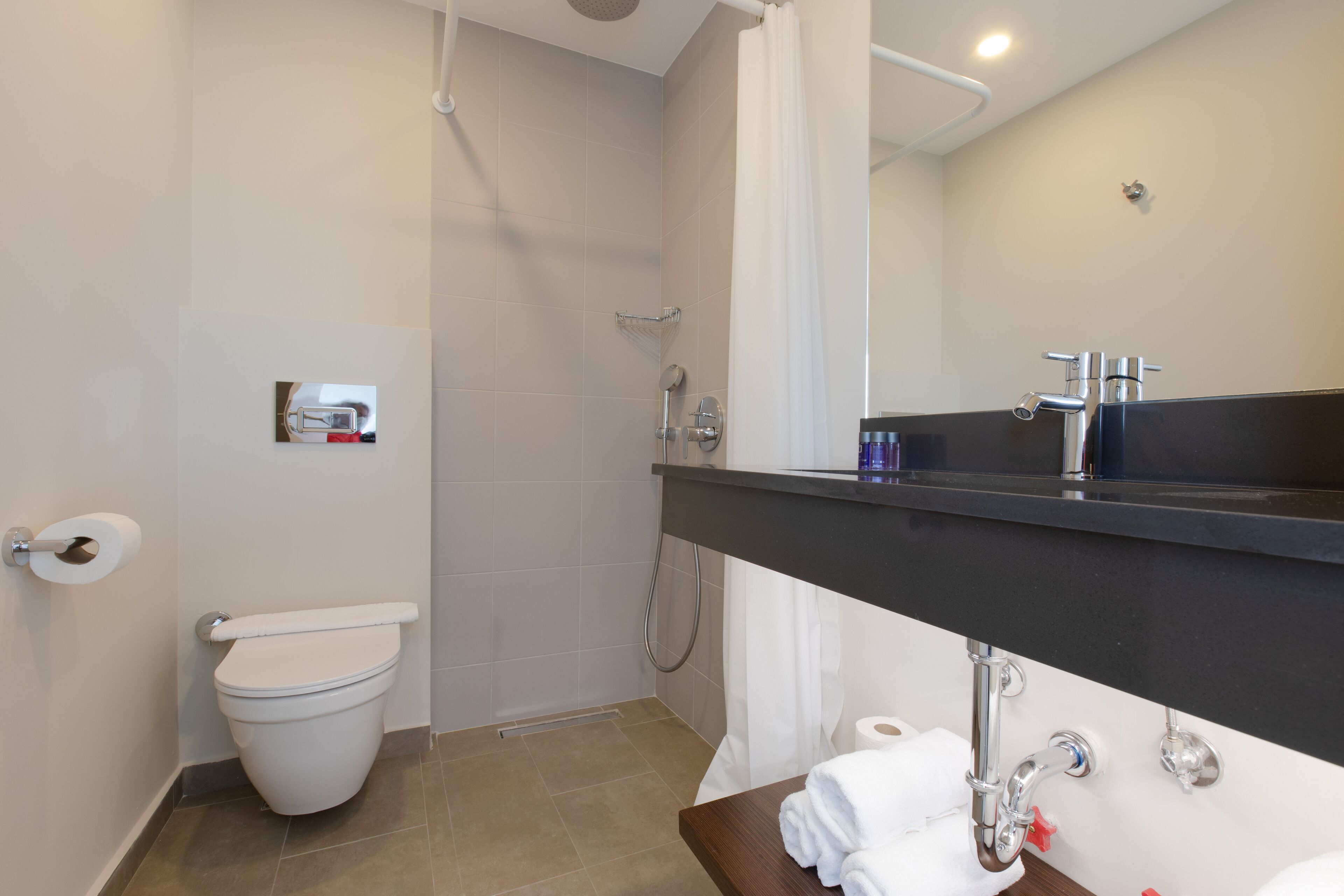 Un baño moderno con inodoro, ducha y lavamanos.