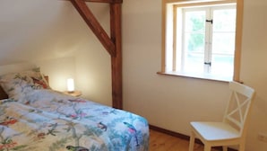 A bedroom with a bed, a window, and a chair. - The Gardener's House - Zinzow Castle (Boldekow)