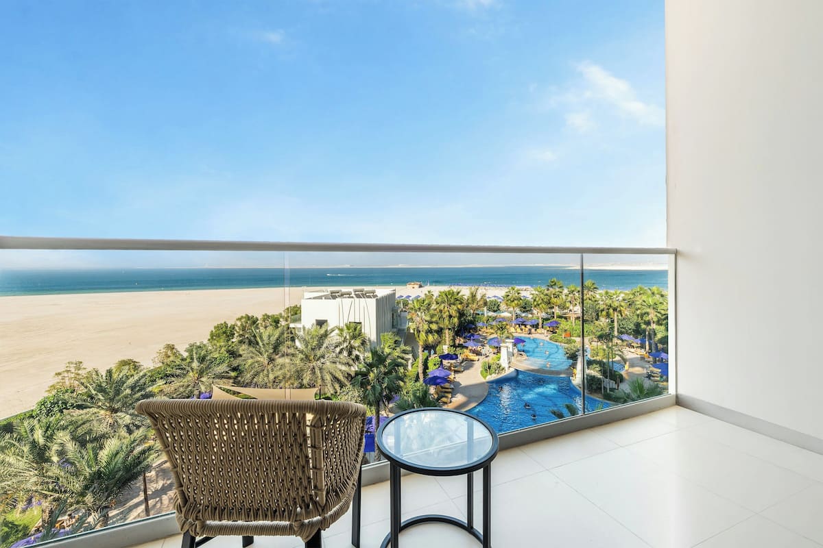 A balcony with a view of a beach and a pool area.