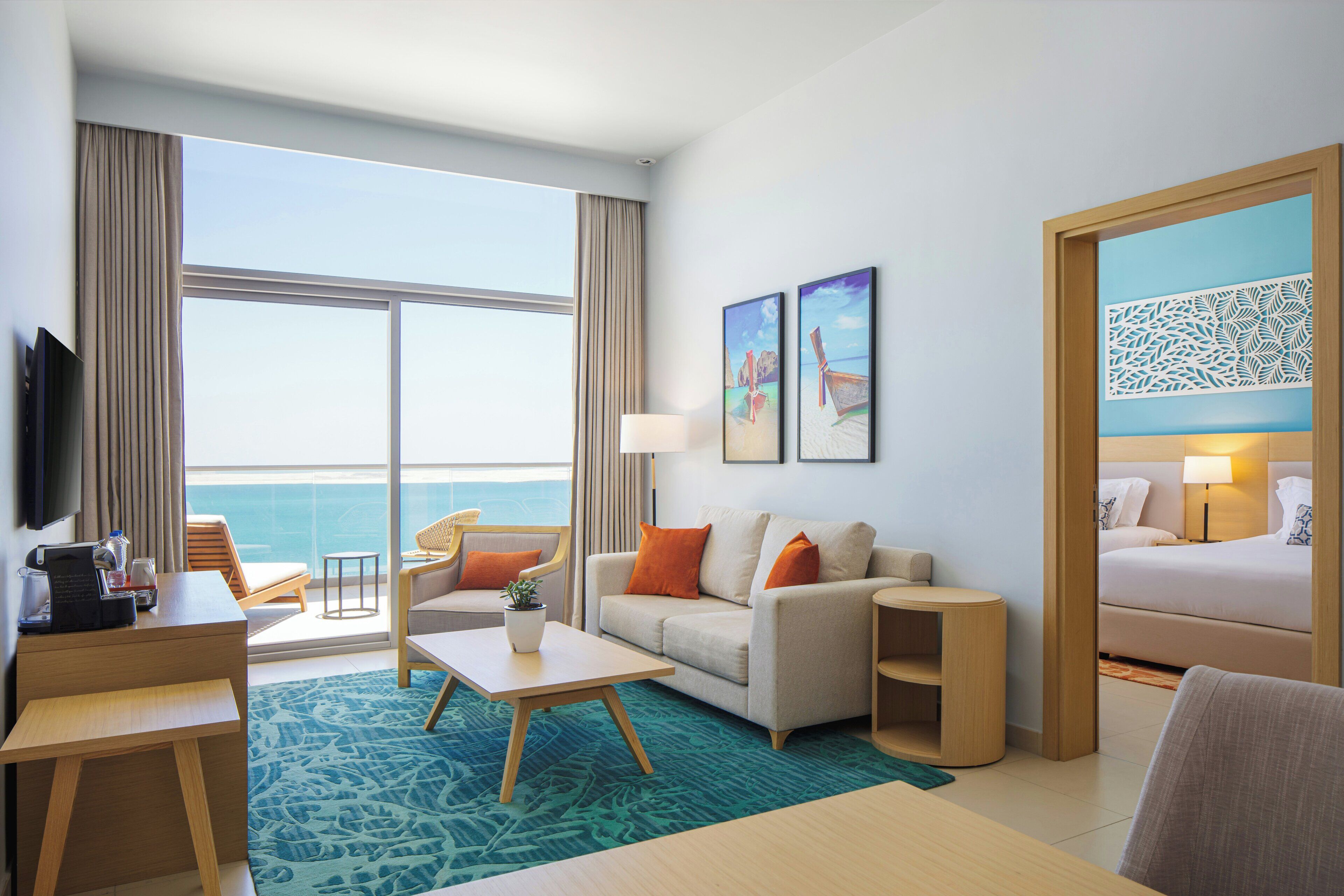A hotel room with a large window, a sofa, a desk, a bed, and a TV.
