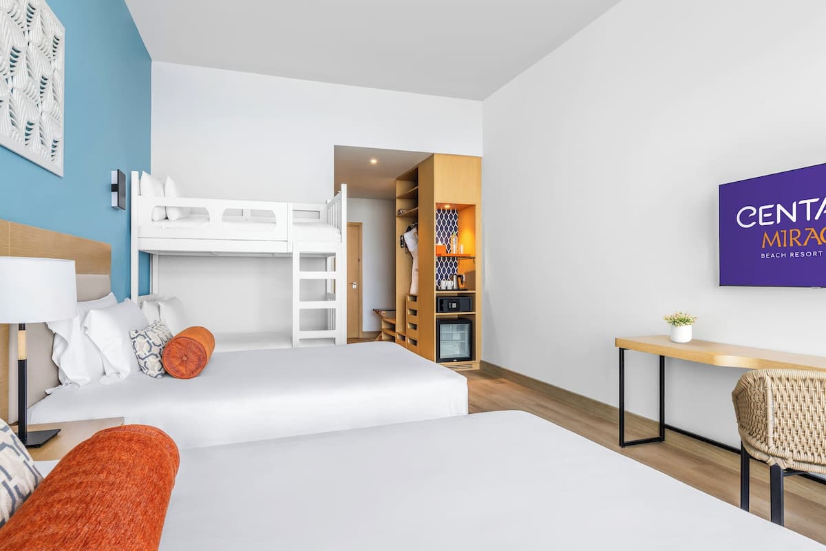 A hotel room with a bunk bed, a desk, a chair, a TV, and a wardrobe.