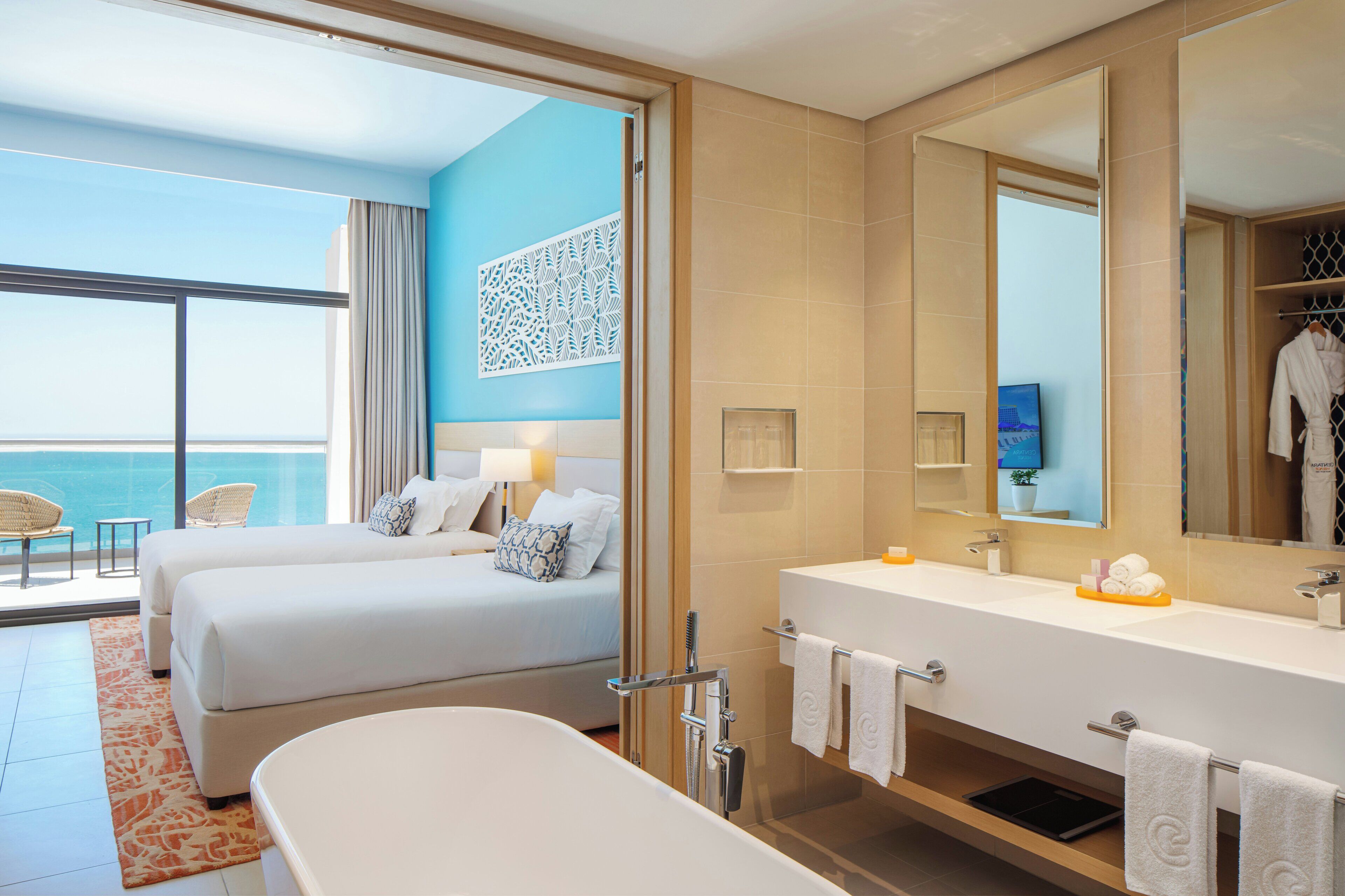 A hotel room with a balcony, a large bathtub, a double bed, and a modern bathroom.