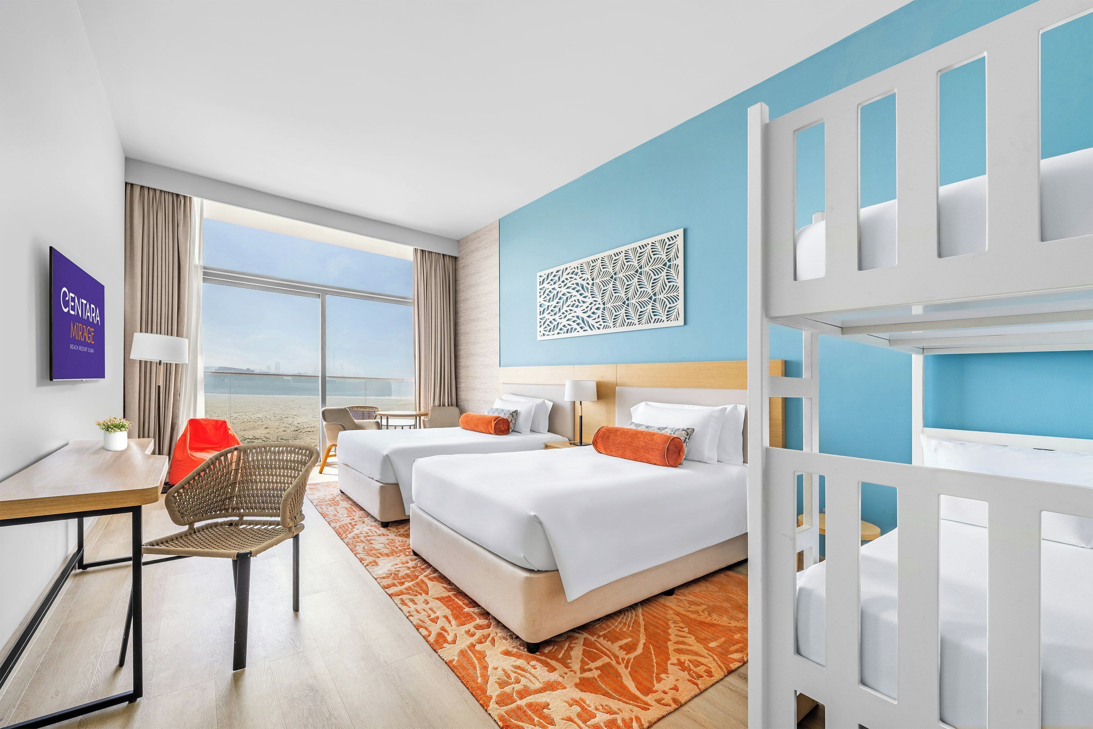 A hotel room with two beds, a desk, a chair, a window with a view, and a decorative wall piece.