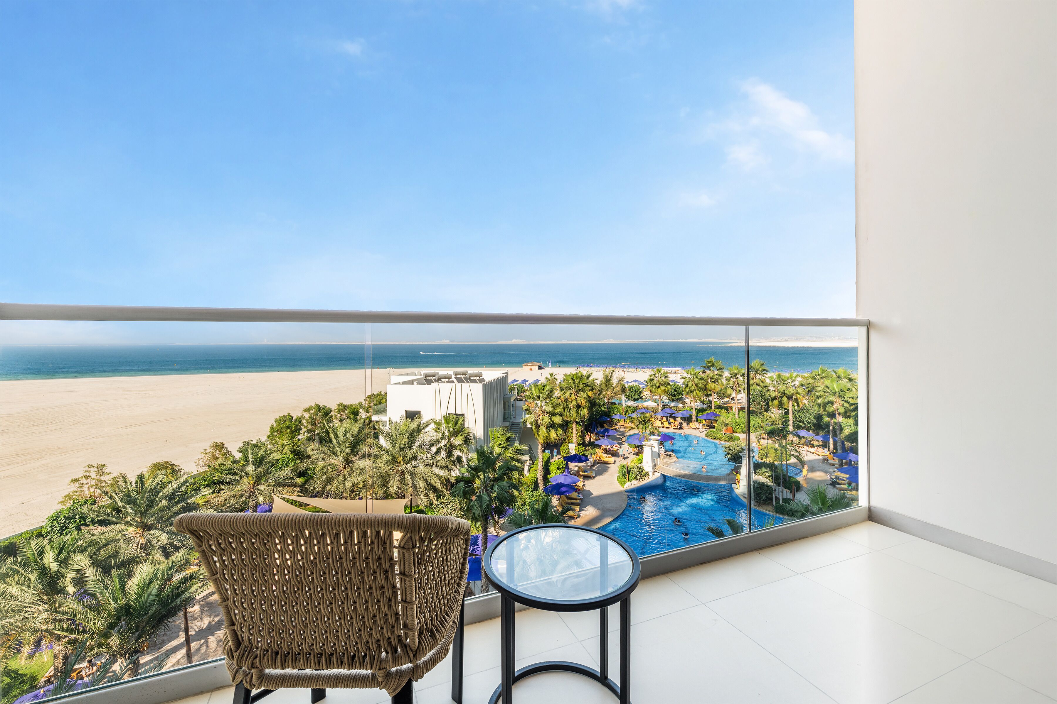 A balcony with a view of a beach and a pool area.