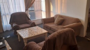 A living room with a sofa, armchair, and a coffee table. - Tasumuka Savaal (Johannesburg)
