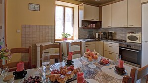 A dining area with a table set for four, a kitchen with basic appliances, and a window with curtains.