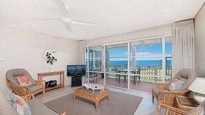 A spacious living room with a large sliding glass door leading to a balcony with a view of the ocean. - Quarterdeck 20 - Spectacular Ocean Views (Lennox Head)