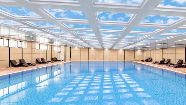 A large indoor swimming pool with a skylight ceiling, lounge chairs along the sides, and a tiled floor. - Crowne Plaza Changsha Development Zone by IHG (Changsha)