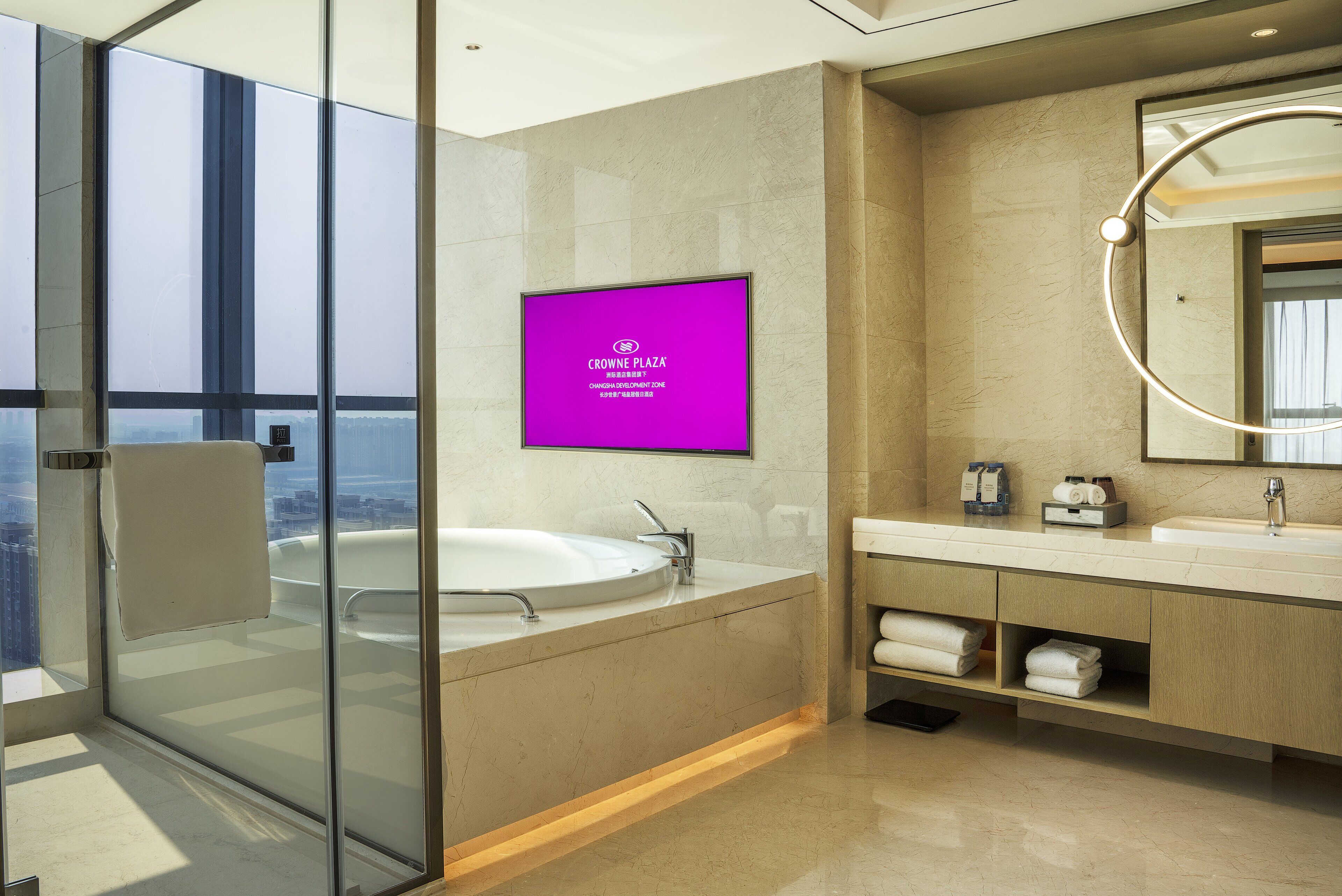 A modern bathroom with a glass-enclosed shower, a large mirror, and a vanity with a sink and towel storage.