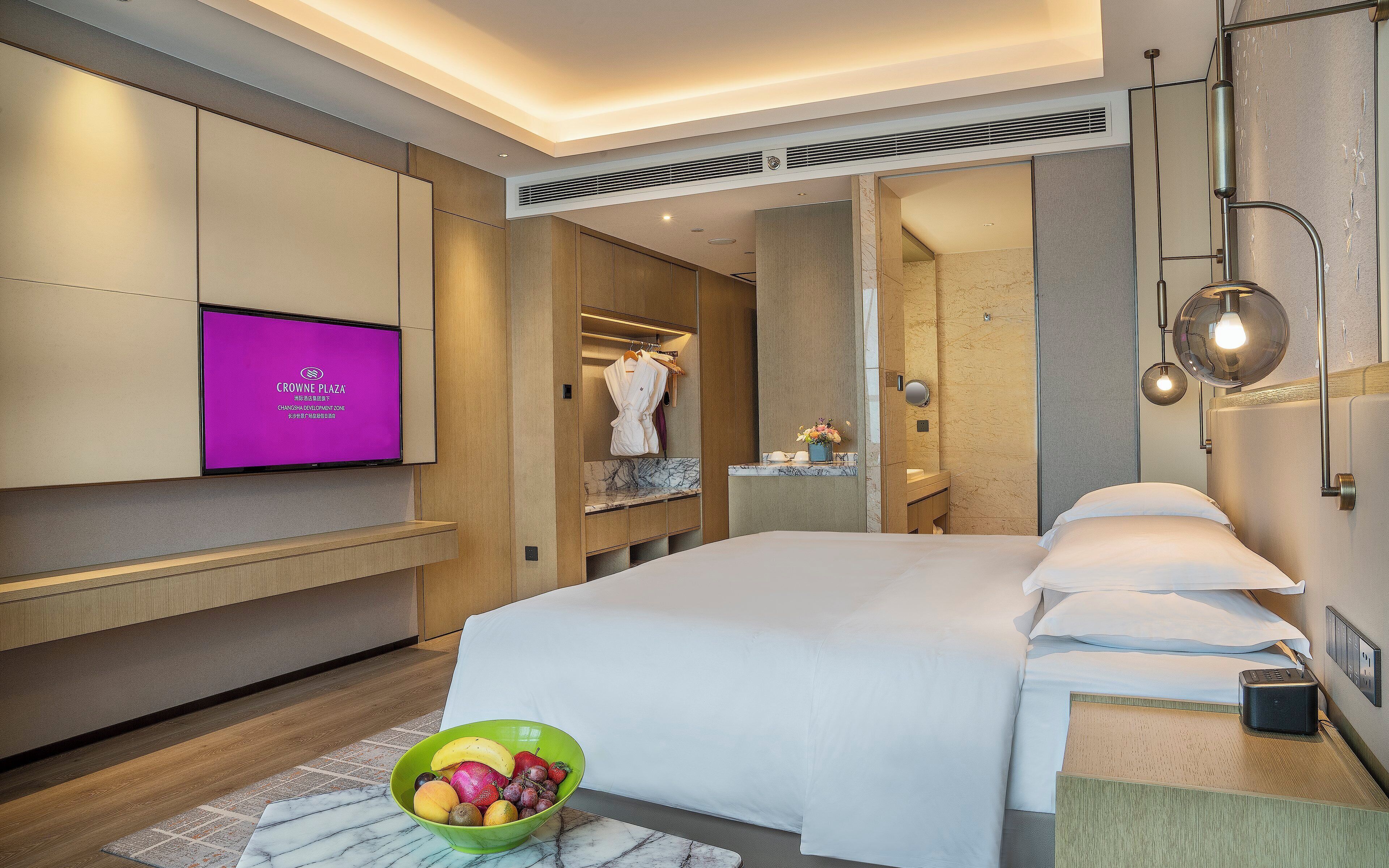 Habitación de hotel con cama, televisión, baño y frutero.