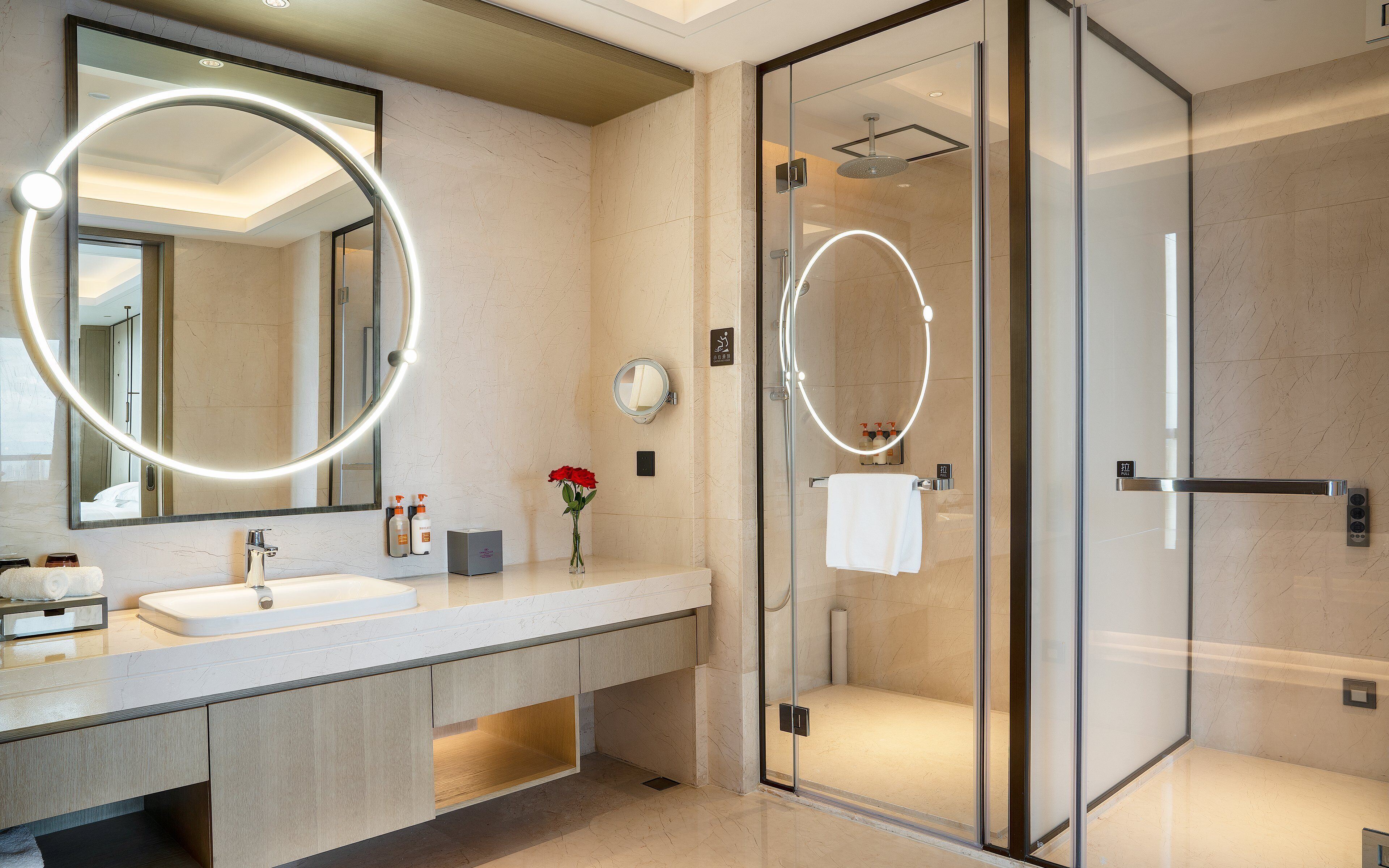 A modern bathroom with a large mirror, a glass shower enclosure, and a vanity with a sink.
