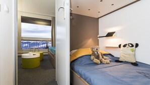 Une chambre à coucher avec un lit, une fenêtre donnant sur un beau paysage, une lampe de chevet et un ours en peluche.