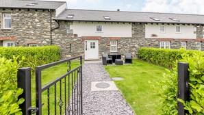 A stone building with a white exterior, a gravel pathway, and a small patio area with outdoor furniture.