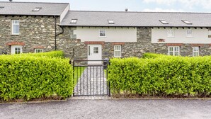 A stone building with a gravel driveway and a metal gate.