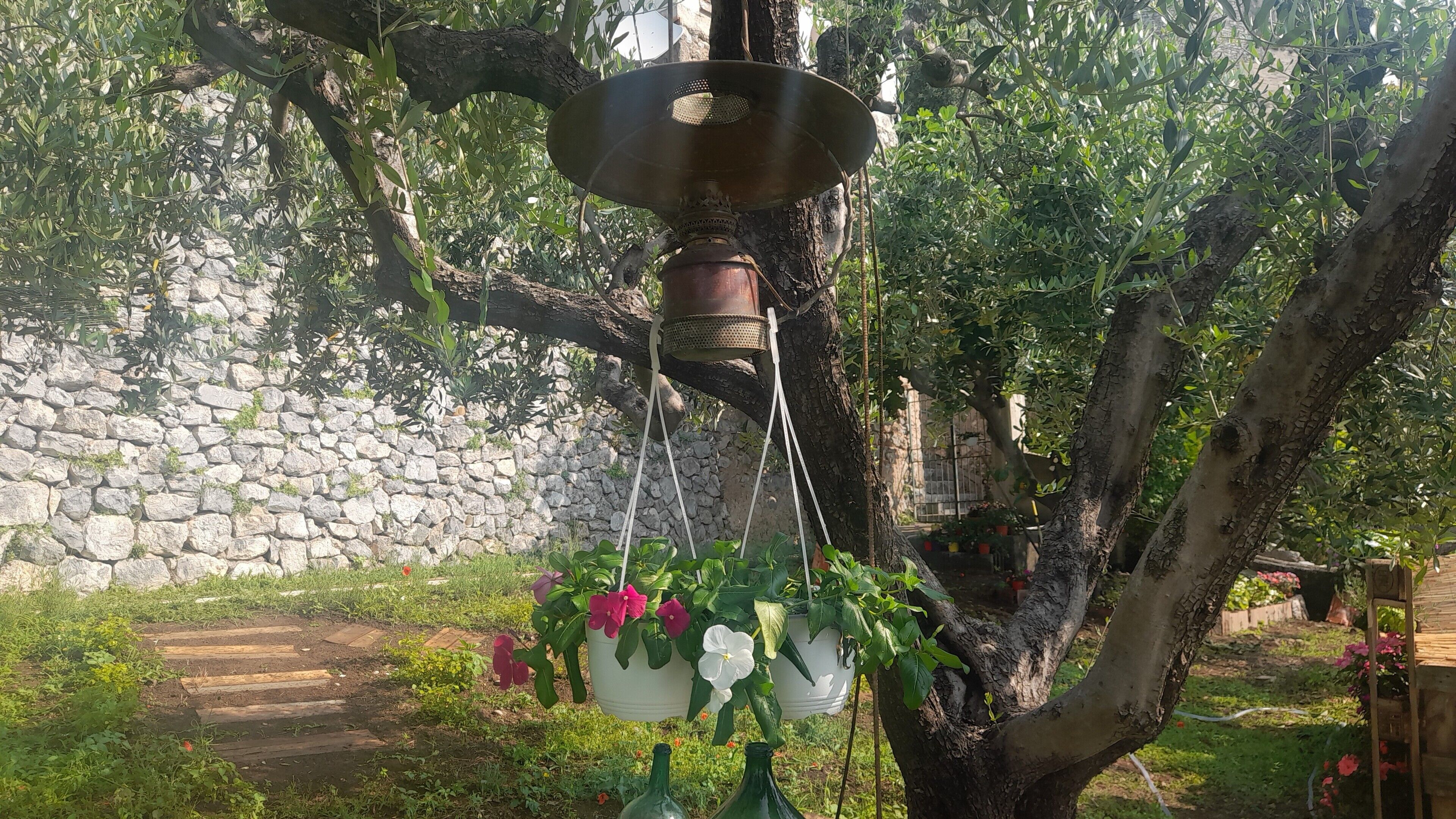 A hanging planter with flowers and a rustic metal lamp.