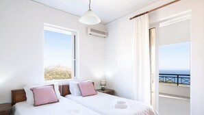 Habitación de hotel con dos camas, un balcón con vistas y un ventilador de techo.