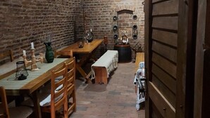 A rustic dining area with brick walls, wooden tables, and benches.