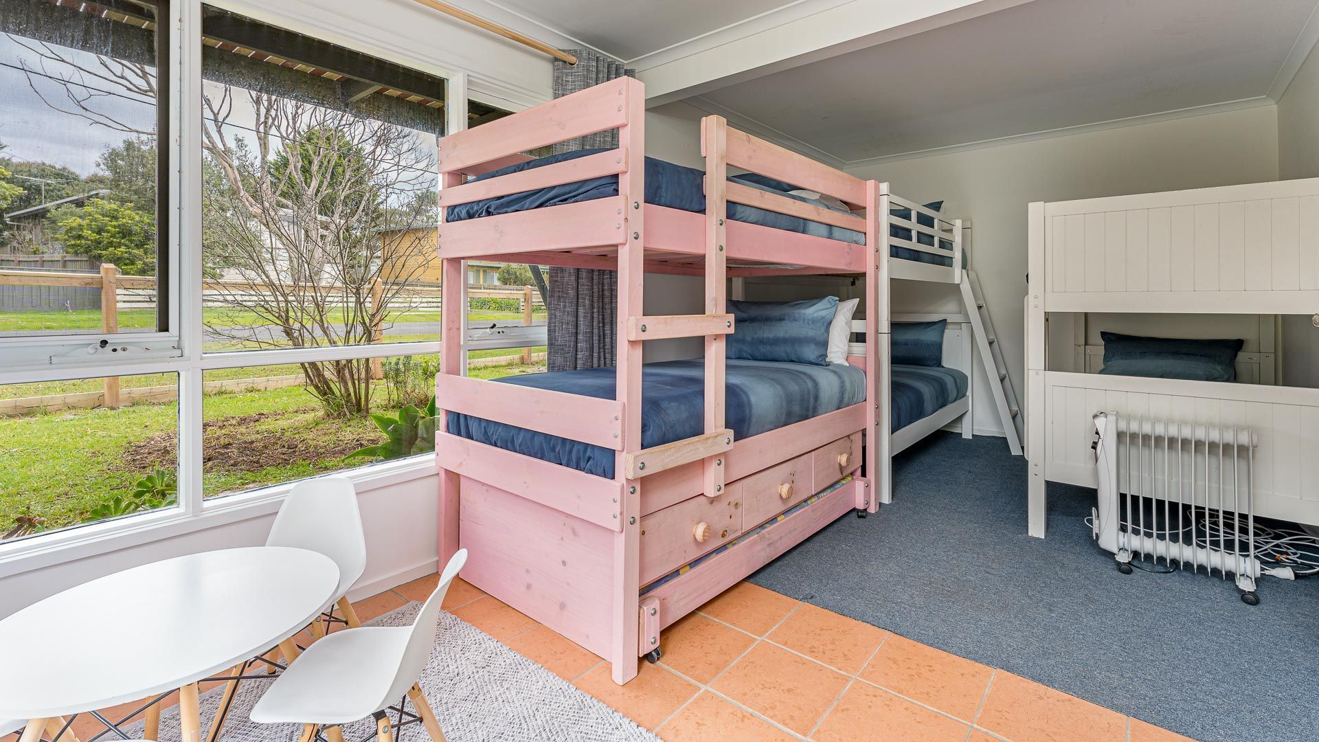 A bunk bed room with a view of the outdoors, a white table, and a radiator.