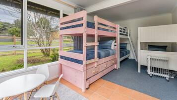 A bunk bed room with a view of the outdoors, a white table, and a radiator.