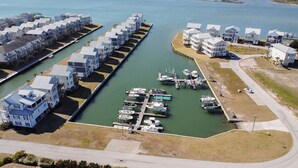 Un puerto deportivo con varias embarcaciones amarradas y una hilera de casas frente al agua.