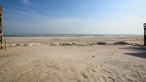 A sandy beach with footprints and a lifeguard tower. - Oceanfront bliss awaits you at Cool Story, a 3BR retreat in North Topsail Beach. (North Topsail Beach)