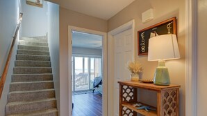 A staircase leading to a room with a view, a wooden console table with decorative items, and a framed picture on the wall. - Oceanfront bliss awaits you at Cool Story, a 3BR retreat in North Topsail Beach. (North Topsail Beach)