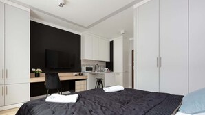 Une chambre moderne avec un grand lit, un bureau et une télévision.