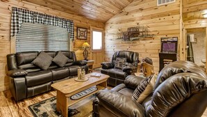 A cozy log cabin interior with a leather sofa set, a wooden coffee table, and a fireplace.