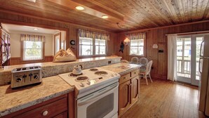 A kitchen with wooden paneling, a granite countertop, a stove, a toaster, and a refrigerator.