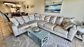 Una sala moderna con un sofá modular, una mesa de centro y un comedor con sillas y una mesa.