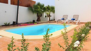 Ein Schwimmbecken mit zwei Liegestühlen und einer Palme.