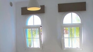 Ein Zimmer mit zwei Einzelbetten, einem Nachttisch mit Lampe und zwei Fenstern mit Jalousien.