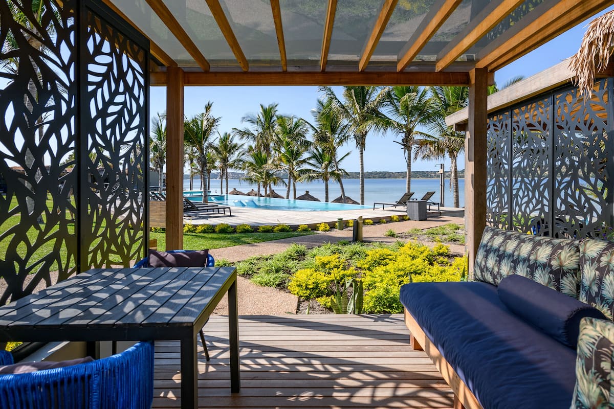 A covered outdoor area with a pool, lounge chairs, and a wooden deck.