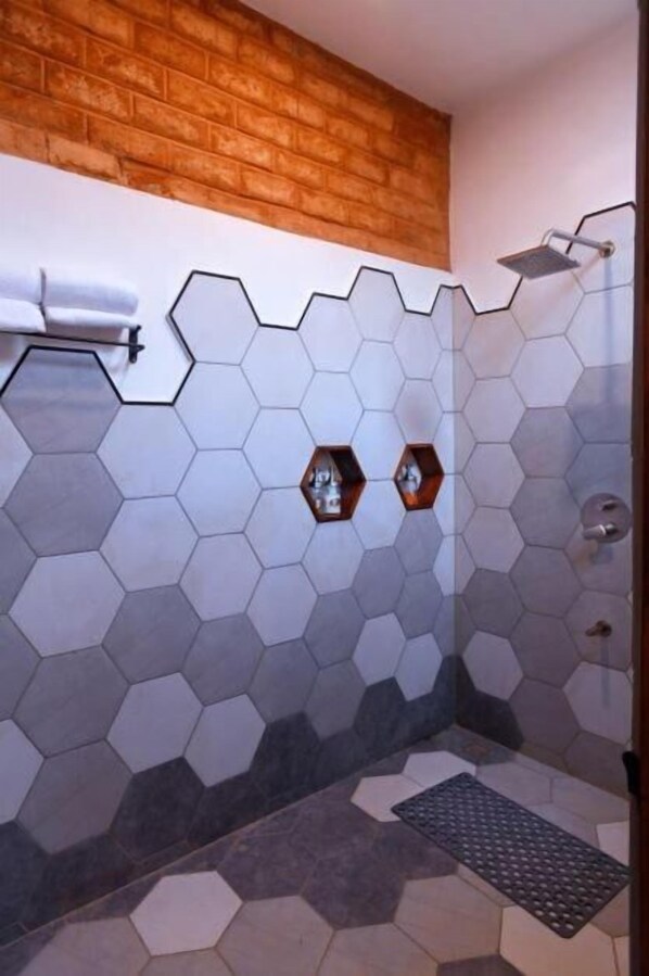 A shower with a hexagonal tile pattern, a wooden accent wall, and a towel rack. - Wagoba Eco lodge (Bhadravathi)