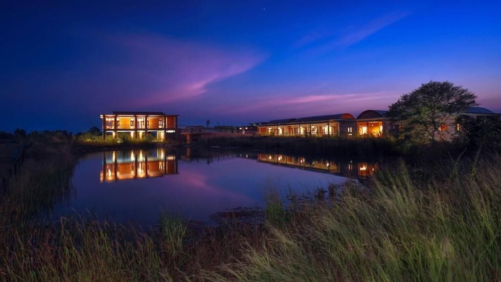 A waterfront property with multiple buildings, a calm body of water, and a clear night sky.