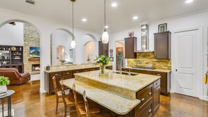 A spacious kitchen with a large island, built-in appliances, and a stone accent wall.