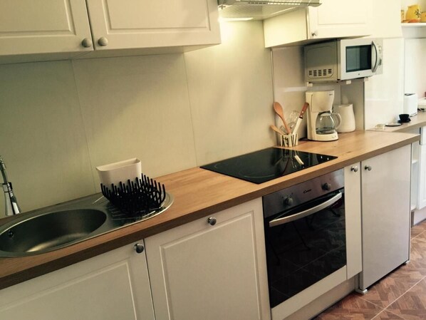 A kitchen with white cabinets, a black stove, a microwave, and a coffee maker.