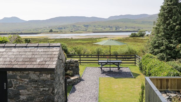 A stone building with a grassy yard, a picnic table, and a view of a lake and hills. - Minffordd (Blaenau Ffestiniog)